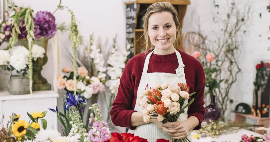 fazer mudas de rosas| Lindo florista posando com buquê