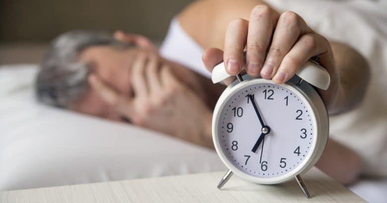 Remédio para Dormir | Homem deitado na cama desligando um despertador de manhã às 7 da manhã. Homem atraente dormindo em seu quarto. Homem irritado sendo despertado por um despertador em seu quarto